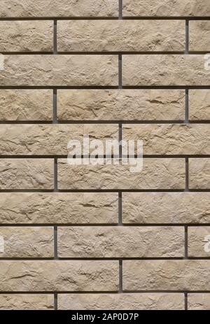 Brick wall with uneven rough beige brick. Decorative wall decoration with brick stone, texture background backdrop. Wall of yellow gray smooth brick t Stock Photo