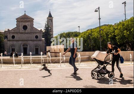 Parents with baby and pet dog walking past church in Avezzano in Abruzzo Italy. Stock Photo