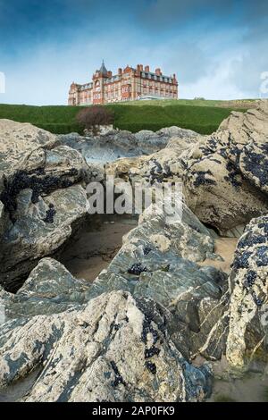 The Headland Hotel overlooking rocks exposed at low tide on the coast at Fistral in Newquay in Cornwall. Stock Photo