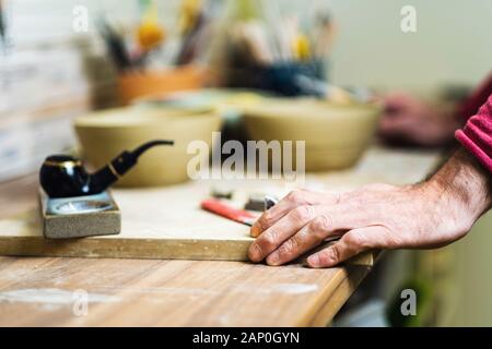 Potter checking tools on pottery studio table, hands detail, shallow debt of field, small art business concept Stock Photo