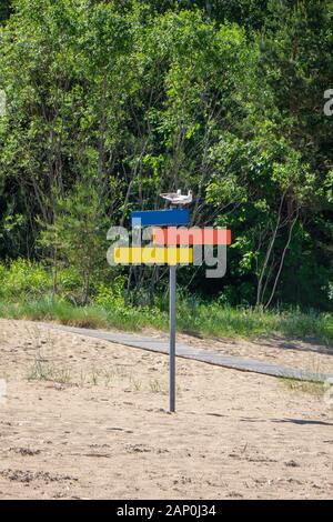 Colorful wooden signpost of directions on a sand beach. Stock Photo