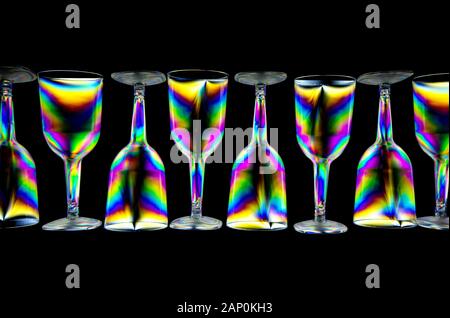 Colourful stress patterns in hard plastic, revealed by imaging between two crossed polarising filters showing a pattern of plastic wine glasses Stock Photo