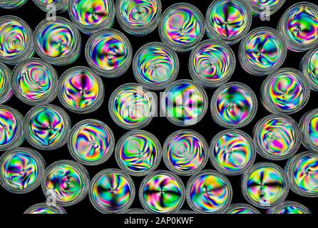 Colourful stress patterns in hard plastic screw top containers  revealed by imaging between two crossed polarising filters. Stock Photo