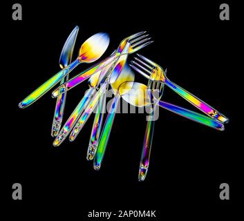 Colourful stress patterns in hard plastic, revealed by imaging between two crossed polarising filters showing a collection of plastcic cutlery. Stock Photo