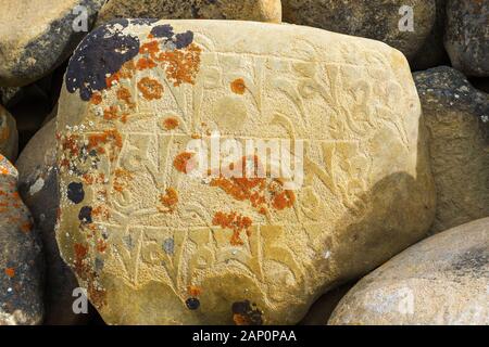 A carved stone with Buddhist mantra on a mani wall in the Nepal Himalayas Stock Photo