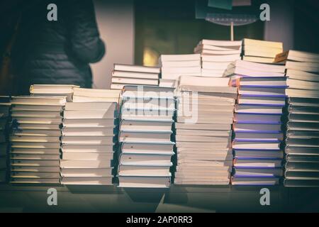 Close-up of stacks of books, textbooks, fiction in rows lying on table, on shelves in library, in modern urban bookshop. Education, school, study conc Stock Photo