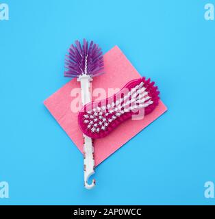 plastic pink brush and square dishwashing rag on a blue background, top view, flat lay Stock Photo