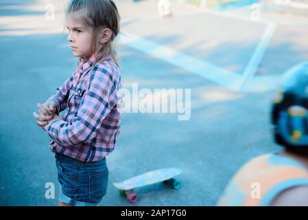 Beautiful young tattooed woman with his longboard on the road in the city in sunny weather Stock Photo