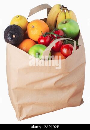 Brown shopping bag filled to overflowing with a variety of fresh fruit. Cut out isolation on white background. Stock Photo