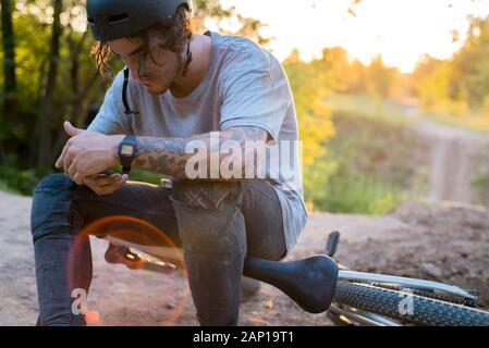 People, sports, active lifestyle and modern technology. Outdoor picture of cyclist on booster bike using navigator on smart phone, exploring map and s Stock Photo