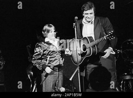 Johnny Cash, amerikanischer Country Sänger und Songschreiber, mit einem kleinen Jungen bei einem Konzert in Hamburg, Deutschland um 1981. American country singer and song writer Johnny Cash performing with a little boy at Hamburg, Germany, around 1981. Stock Photo