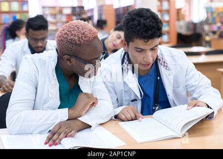 medical education, health care, people and medicine concept - group of happy doctors or interns with mentor meeting and taking notes at hospital Stock Photo