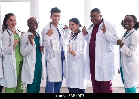 medical students, doctors, mixed race. A team of young people in white coats posing in the hallway of the hospital