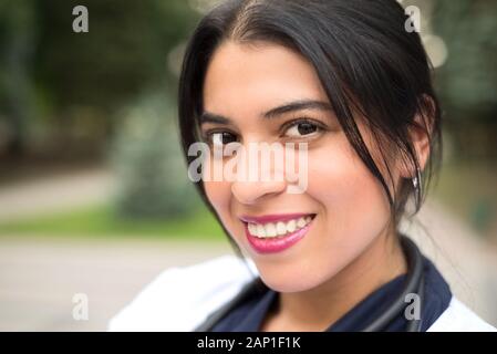 portrait of a beautiful, young mexican girl doctor. Smiles. Woman in a white coat with a stethoscope. Outdoor in Stock Photo