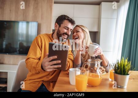 Cheerful couple talking to each other while having breakfast at home. Stock Photo