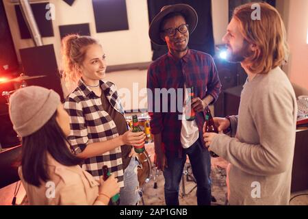 High angle view at multi-ethnic group of young people drinking beer and chatting while enjoying rehearsal in music studio Stock Photo