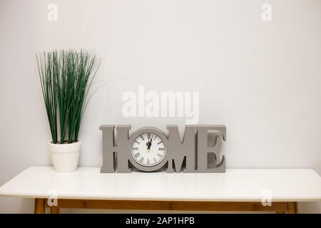 Interior decoration, flower pot and clock, home details, on wooden table against white wall, copy space Stock Photo