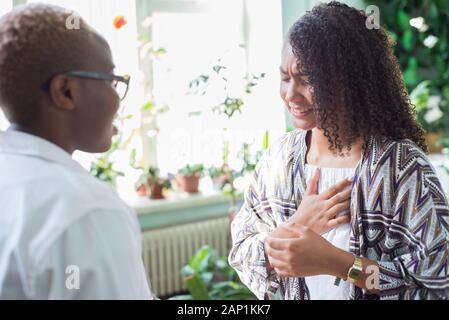 Mexican patient complains of pain in the heart, an African woman doctor, in the office. Mixed race young people Stock Photo