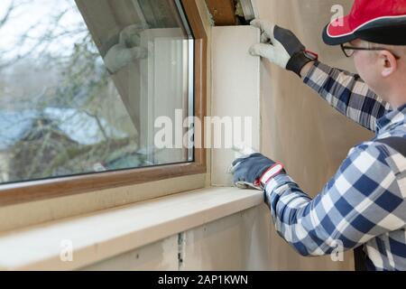 home improvement handyman installing window in new build attic by using leveler and laser leveler Stock Photo