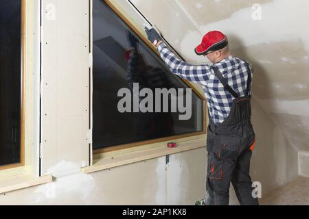 home improvement handyman installing window in new build attic by using leveler and laser leveler Stock Photo
