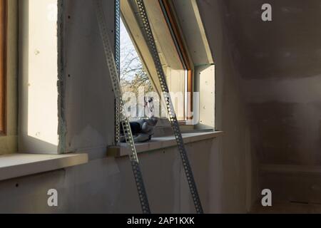 home improvement handyman installing window in new build attic by using leveler and laser leveler Stock Photo