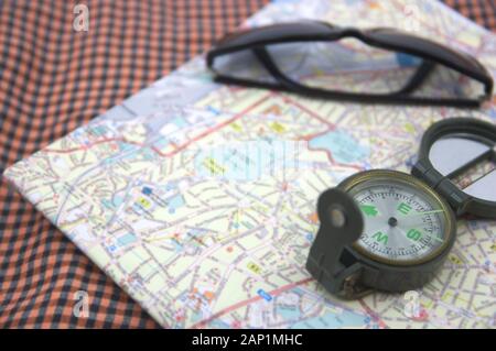 On a table we see a compass and a paper map to find the destination Stock Photo