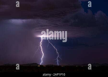 Vivid lightning bolts strike a mountain during a monsoon thunderstorm in the desert near Tonopah, Arizona Stock Photo