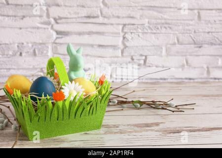 Colorful Easter eggs and Easter bunny in a green basket. Easter background. Happy Easter time. Copy space. Stock Photo