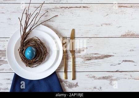 Creative festive Easter table setting on wood background with blue marble colored egg on a nest. Happy Easter time. Stock Photo