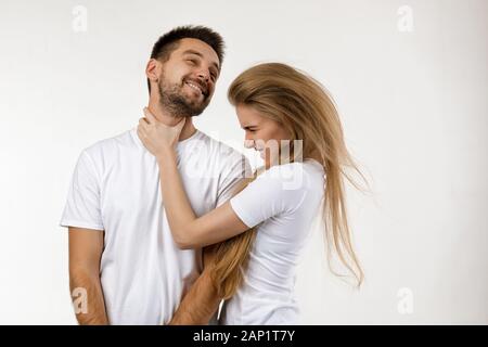 woman jokingly strangles man. angry woman shouting at her happy boyfriend on white background. Stock Photo