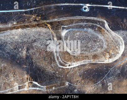 Ice crack pattern in frozen puddle in winter. Stock Photo