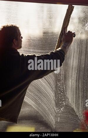 Maintenance worker cleaning a window the large squeegee Stock Photo