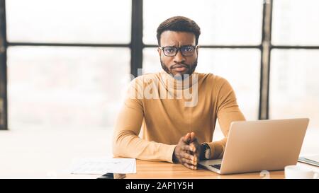 Depressed afro manager looking at camera at work Stock Photo