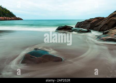 Red stones and rocky shoreline on Black Brook Beach, Cape Breton Highlands National Park, Nova Scotia, Canada. Scenic natural landscape Stock Photo