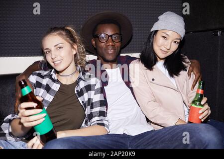 Portrait of handsome African man posing with two young women in nightclub, shot with flash Stock Photo
