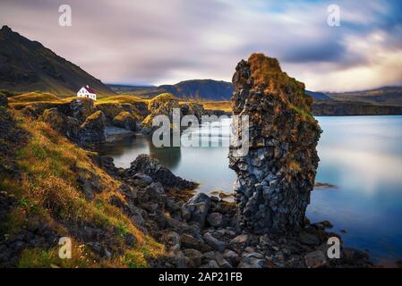 Sea shore in Iceland with cliffs and a small house in the village of Arnarstapi Stock Photo