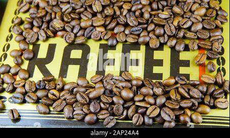 Isolated single word black coffee (German: Kaffee) on golden metallic  ground with roasted brown countless beans frame Stock Photo