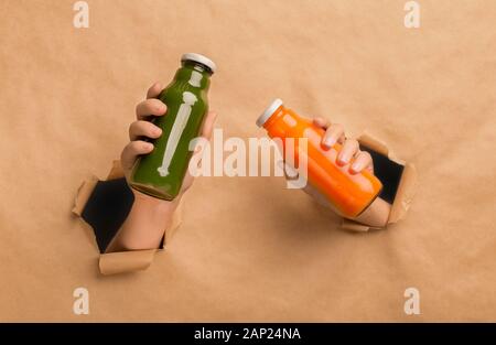 Female holding orange and green detox drink in hands Stock Photo