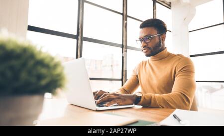 Afro man working on laptop in modern office Stock Photo