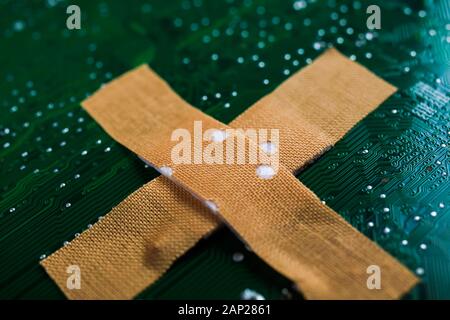 Digital health patient data storage concept - Isolated adhesive plaster on green computer  motherboard (Focus on plaster) Stock Photo