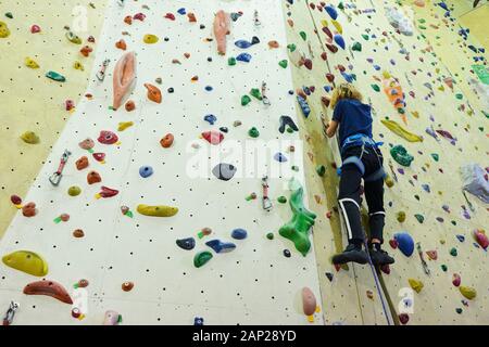 Free climber child young boy practicing on artificial boulders in gym, bouldering Stock Photo