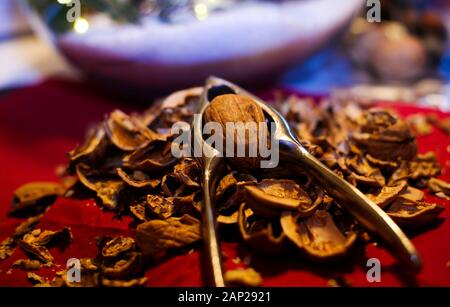 Close up pile with cracked walnut shells and isolated retro lever nutcracker with red background. Stock Photo