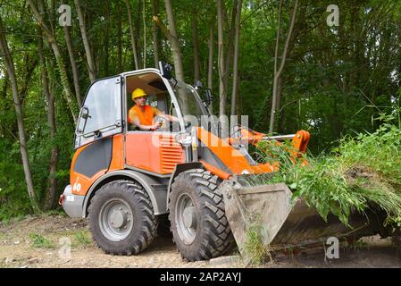 Construction worker drives a small wheel loader on the construction site Stock Photo