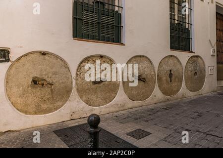 Millstones, mill wheels embedded in facade, protecting wall, Calle Santa Teresa, Barrio Santa Cruz, Sevilla, Andalucia, Spain. Stock Photo