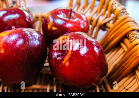Close up of isolated four red dotted shiny isolated dessert apples in wicker reed basket Stock Photo