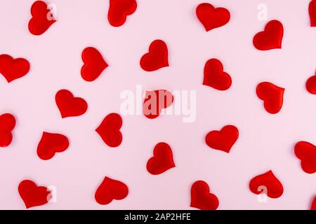 red hearts scattered on a pink background with free space for text