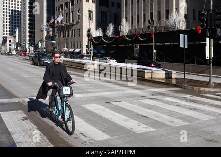 Chicago, USA - December 30, 2018:  Man riding  a blue Divvy rental bicycle on Michigan Avenue.  Bike sharing is a popular option in Chicago, with over