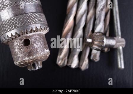 Drill and drills on a workbench. Tools for construction workers. Dark background. Stock Photo