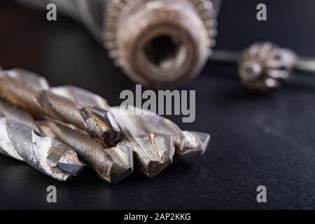 Drill and drills on a workbench. Tools for construction workers. Dark background. Stock Photo