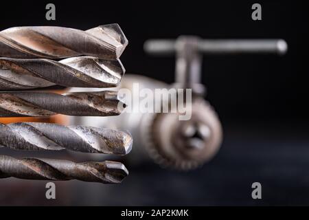 Drill and drills on a workbench. Tools for construction workers. Dark background. Stock Photo